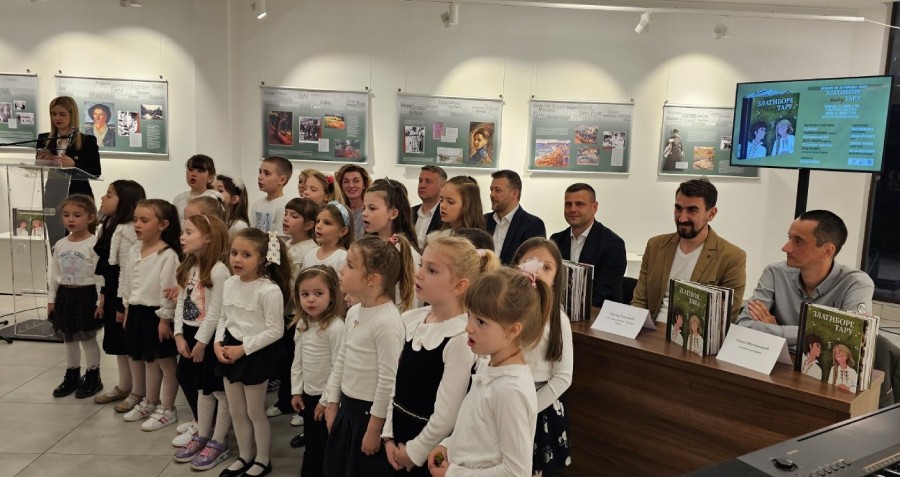 Представљање књиге „Златиборе питај Тару" Деца певају у хору, а иза њих седе одрасли који говоре на представљању књиге