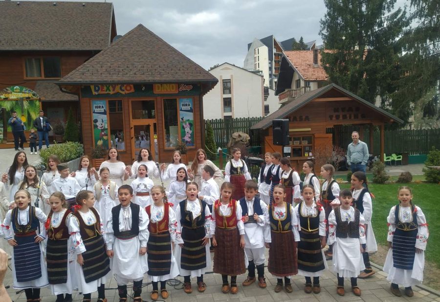 deca u narodnim nosnjama stoje na otvorenom i pevaju
