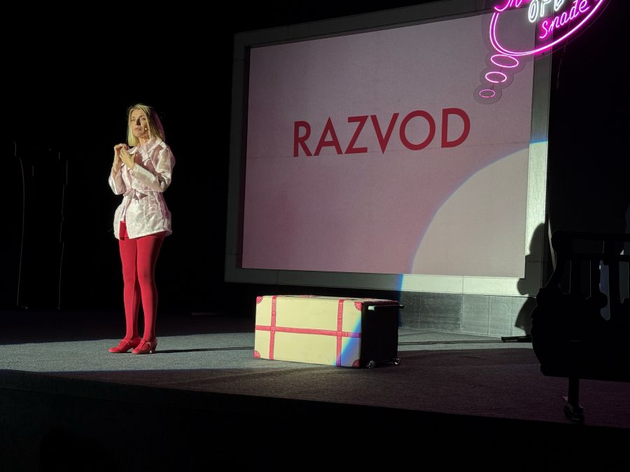 ,,Шта ме опет снађе" zena u crvenim hulahopkama i roze haljini stoji ispred video bima
