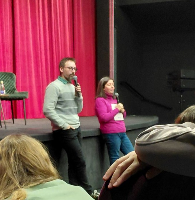 muskarac i zena stoje naslonjeni na binu  