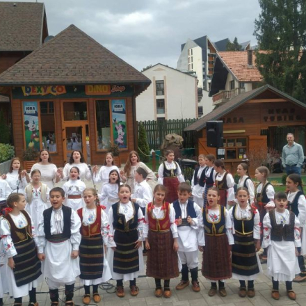 deca u narodnim nosnjama stoje na otvorenom i pevaju