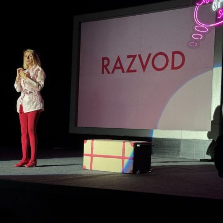 zena u crvenim hulahopkama i roze haljini stoji ispred video bima