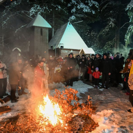 vatra iza koje stoji svestenik i crkva u poyadini